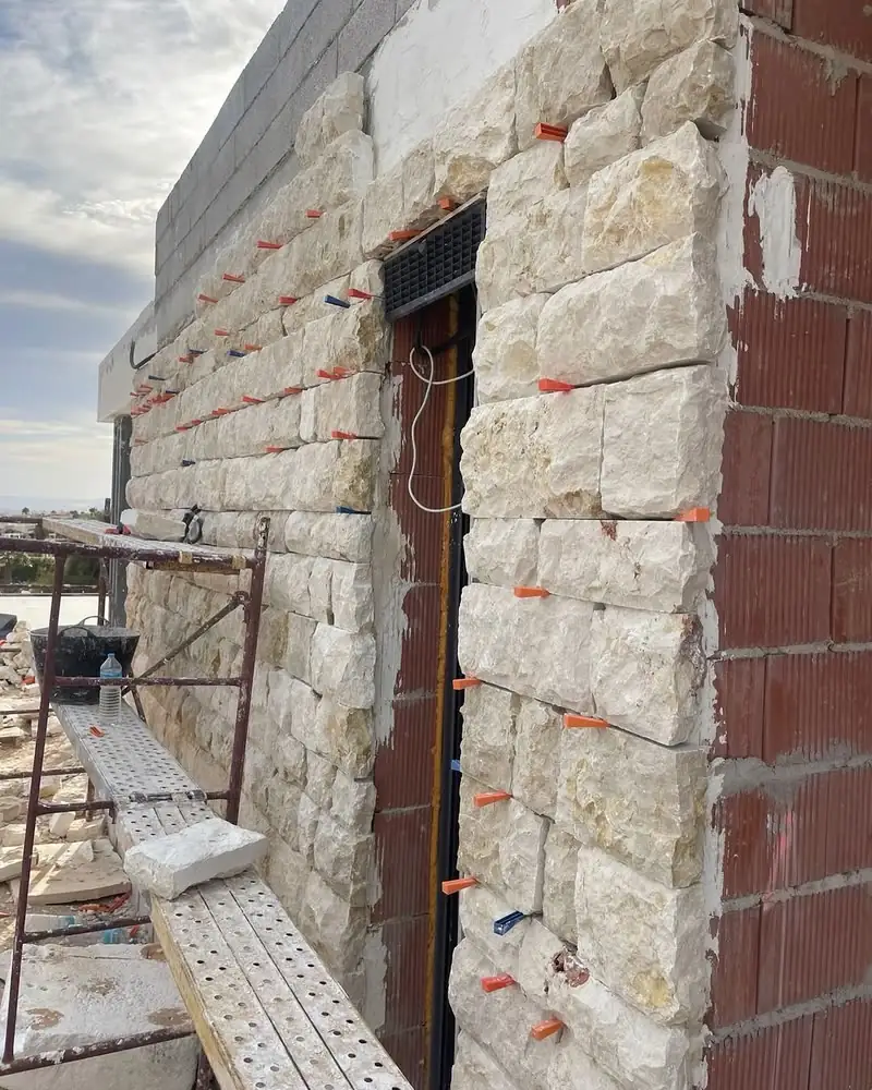 Natural stone facade being installed on scaffolding